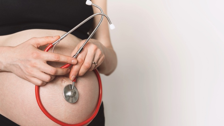 gestante realizando acompanhamento pré-natal com estetoscópio na barriga com um plano de saúde cobre parto normal e parto cesárea