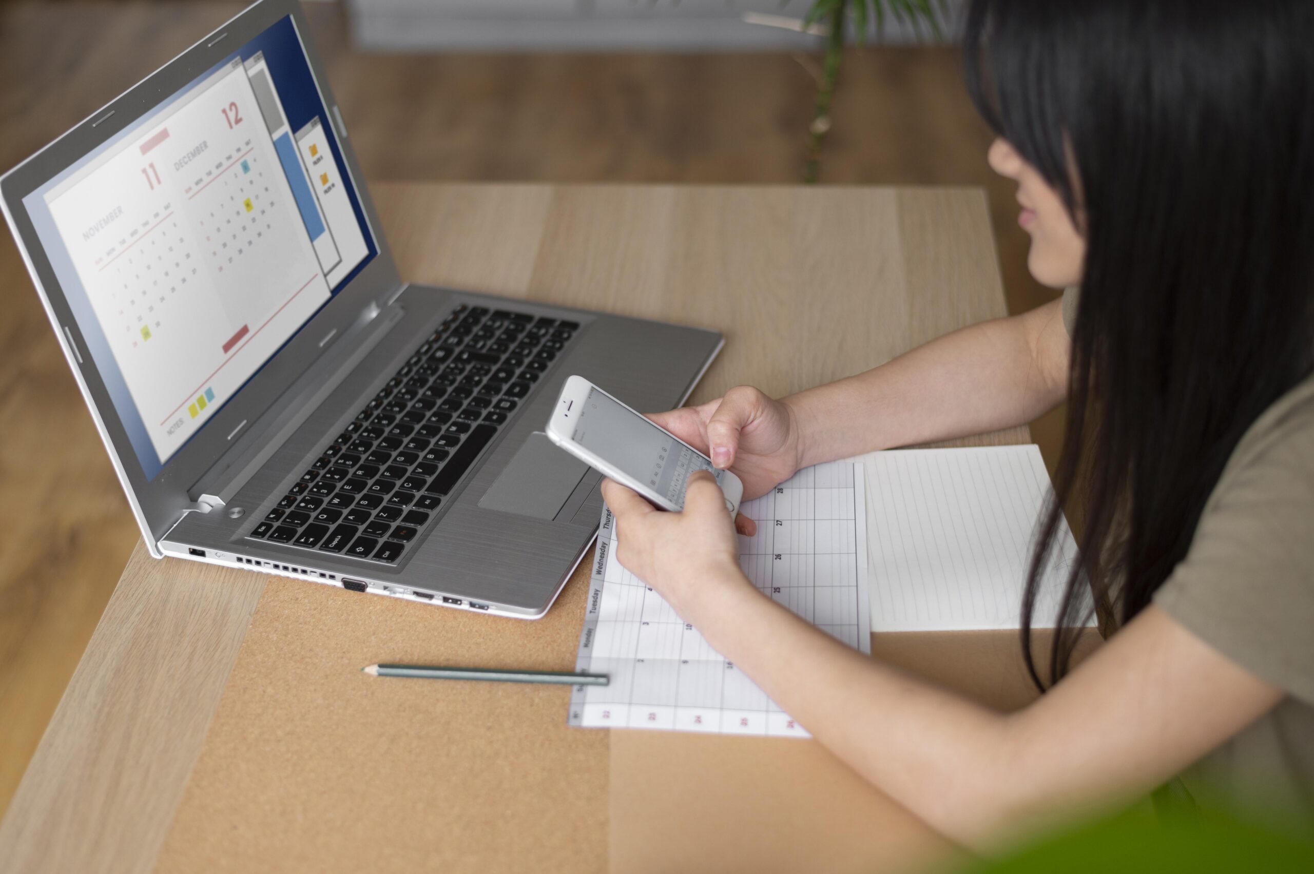 Mulher segurando o celular enquanto consulta o calendário INSS com as datas de pagamento dos benefícios previdenciários.